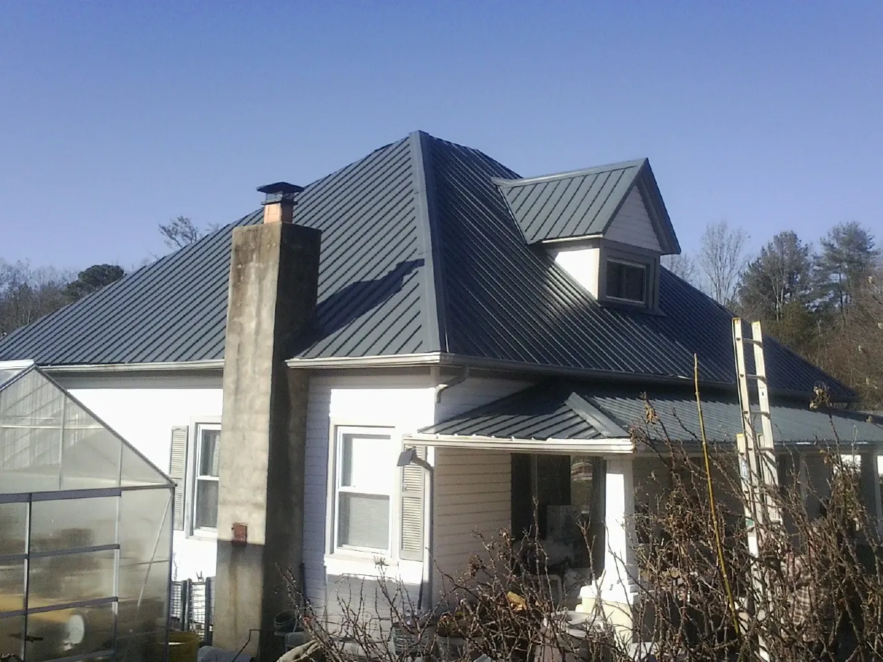 Dark blue standing seam metal roof on a white farmhouse with dormer — Slate & Tile Roof Repair by Roofing Brothers in Burnettsville