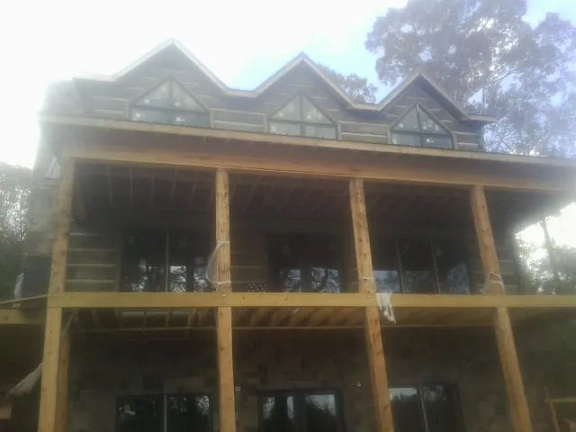 Dormers and porch framing on a large log home under construction — Roof Coating work by our crew in Burnettsville