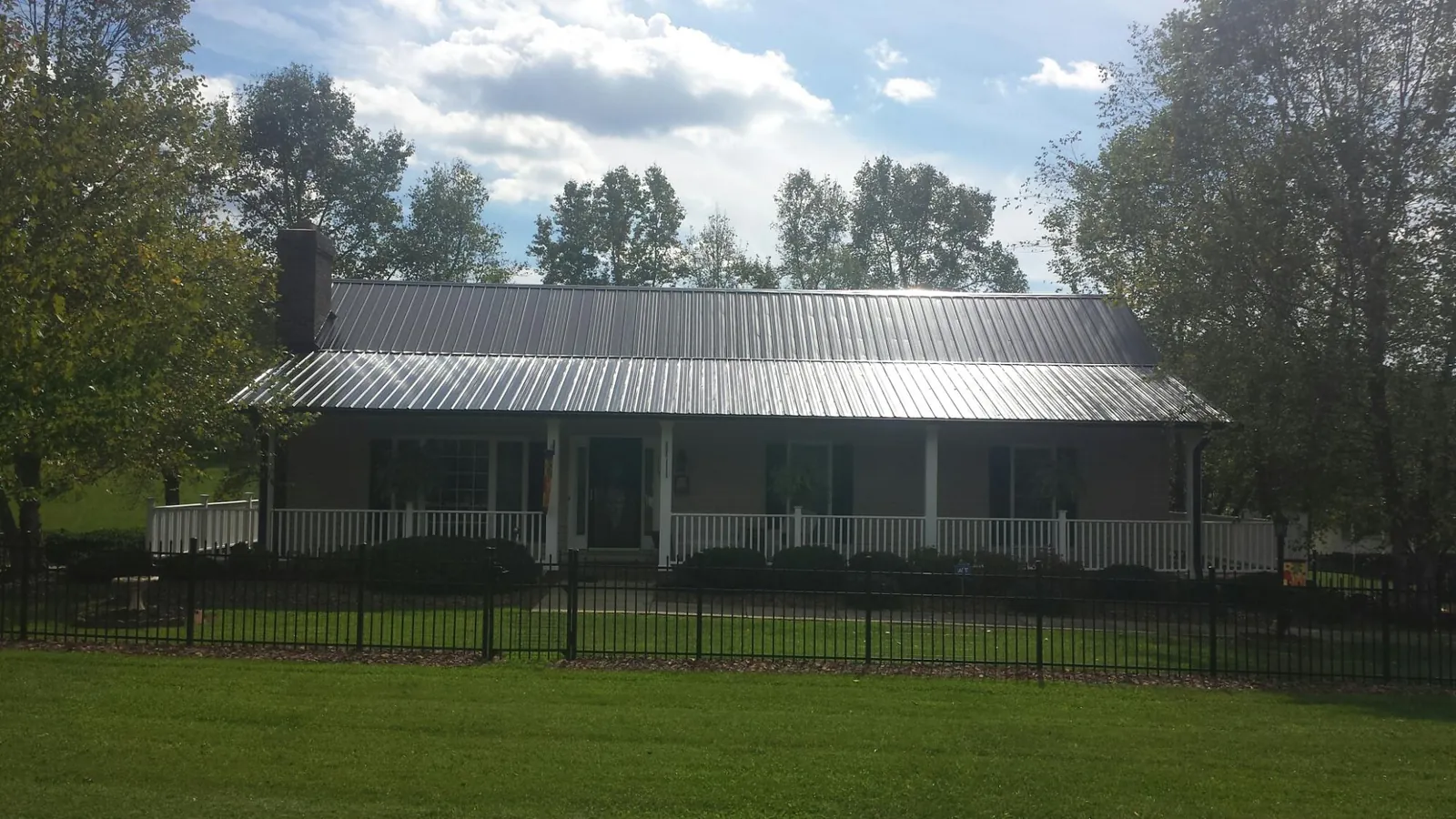 Gray metal roof on a brick ranch with a full width front porch — Gutter Guard Installation work by our crew in Burnettsville