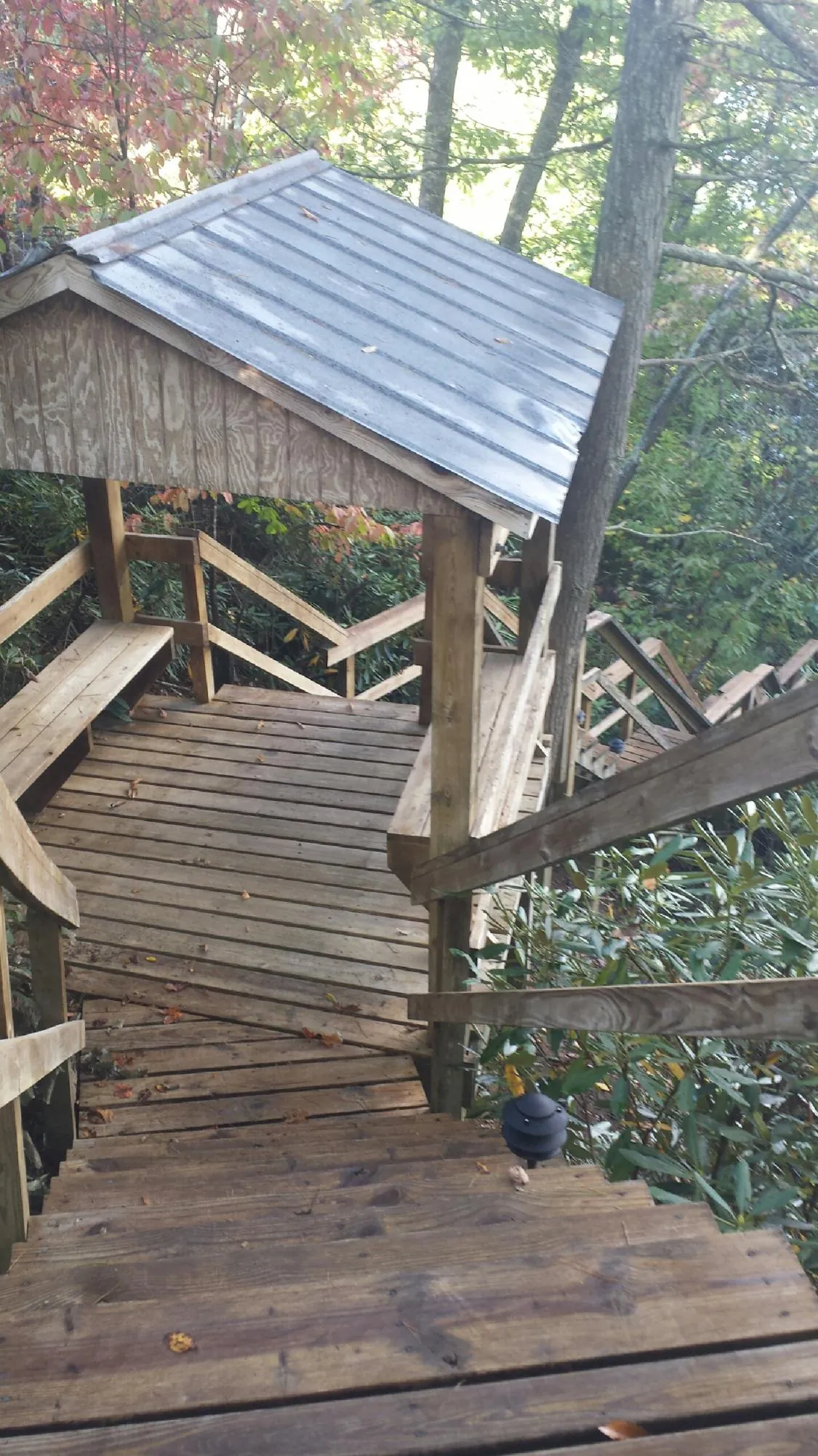Metal roofed shelter over wooden steps on a wooded walkway — Skylight Repair & Installation work by our crew in Burnettsville