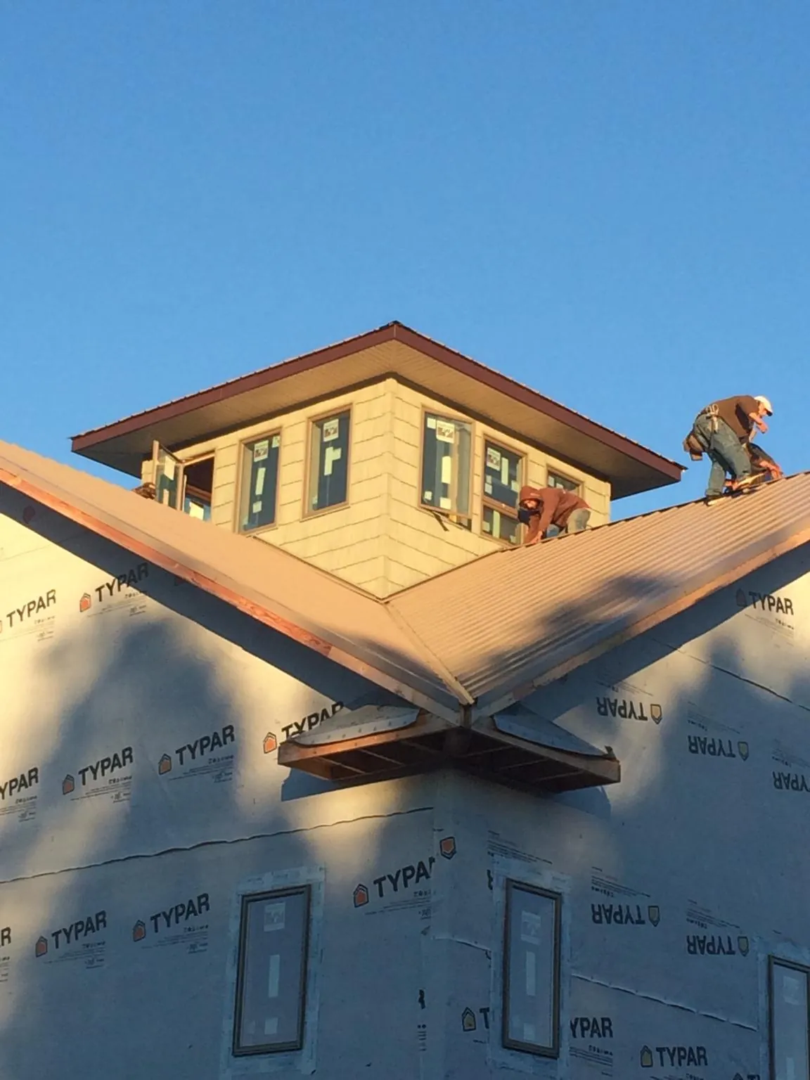 Roofers working around a rooftop cupola on a new metal roof at sunset — Roof Waterproofing in Burnettsville by Roofing Brothers